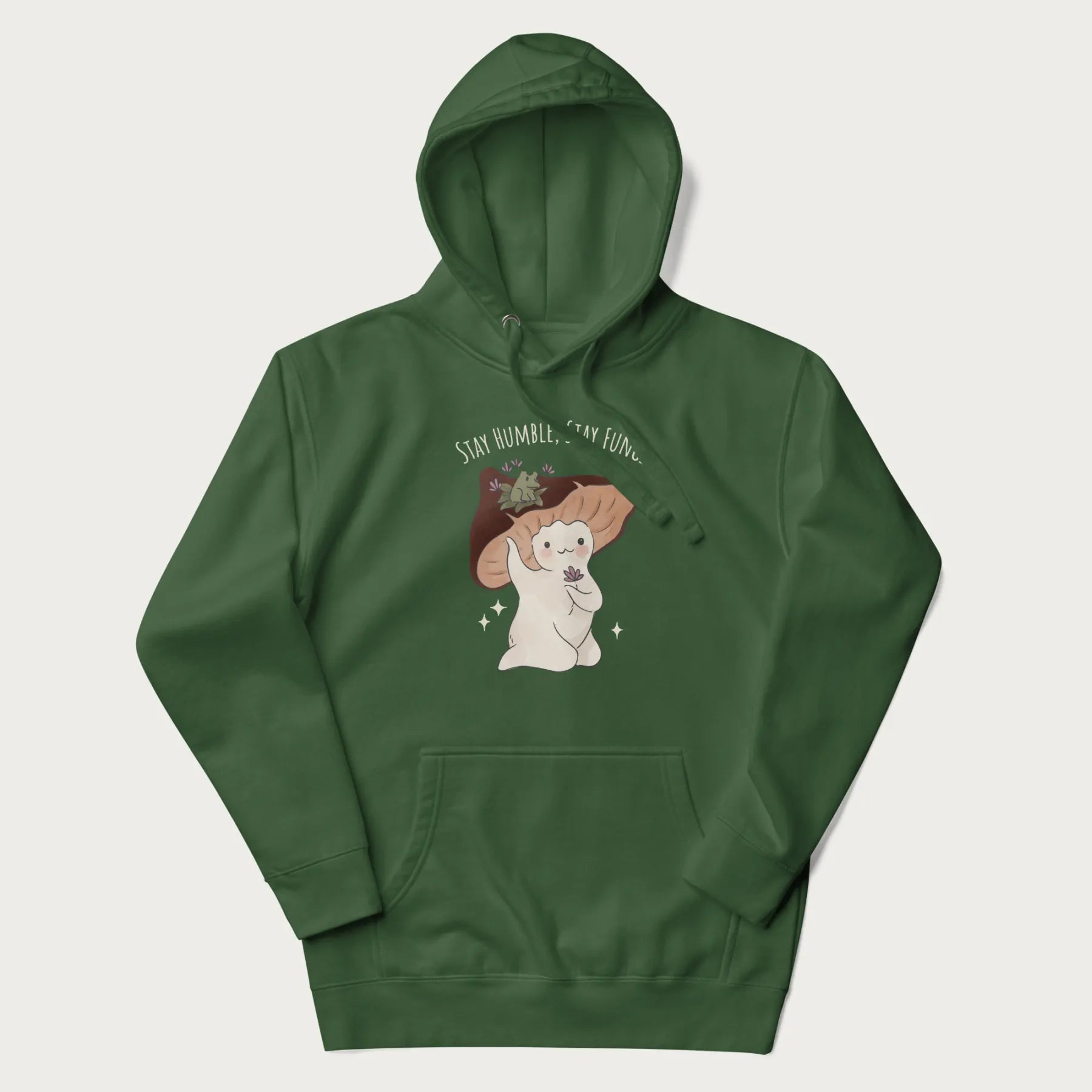 Forest green hoodie with graphic of a cute mushroom character holding a flower with a frog on its cap and the text 'Stay Humble, Stay Fungi' above.