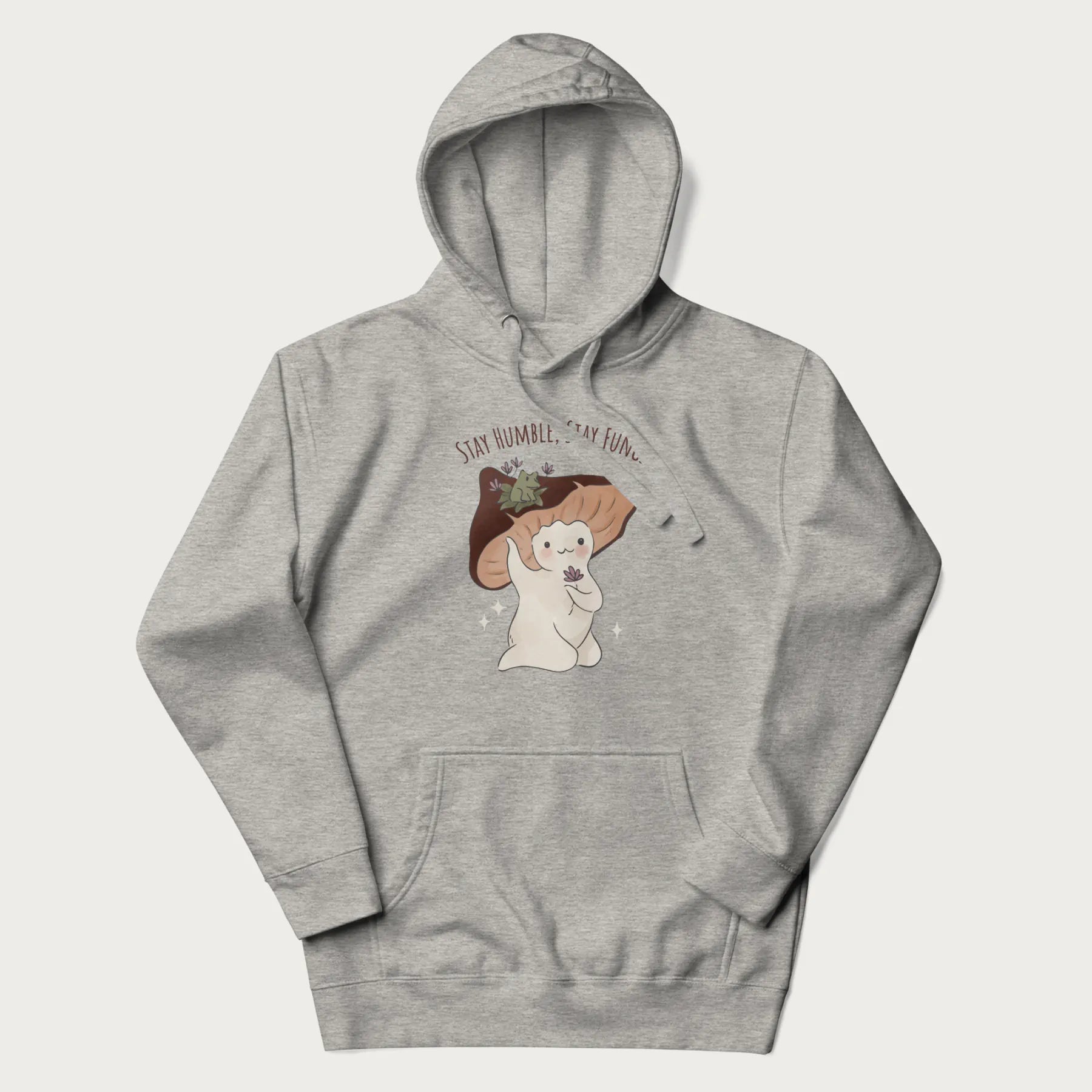 Light grey hoodie with graphic of a cute mushroom character holding a flower with a frog on its cap and the text 'Stay Humble, Stay Fungi' above.