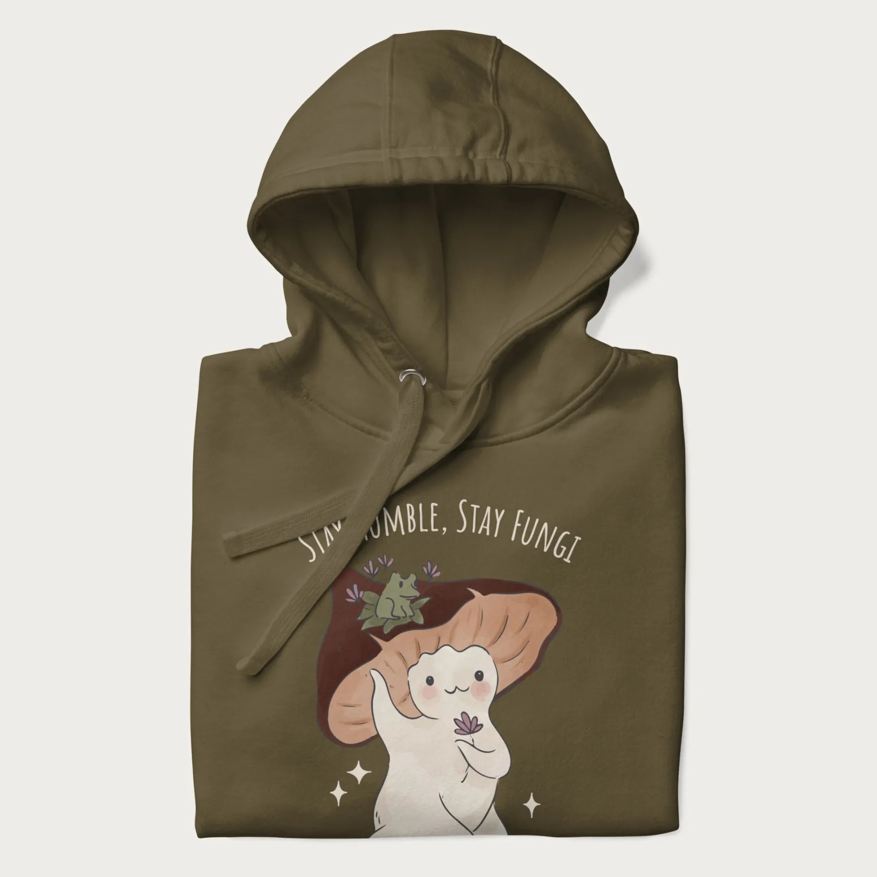 Folded military green hoodie with graphic of a cute mushroom character holding a flower with a frog on its cap and the text 'Stay Humble, Stay Fungi' above.
