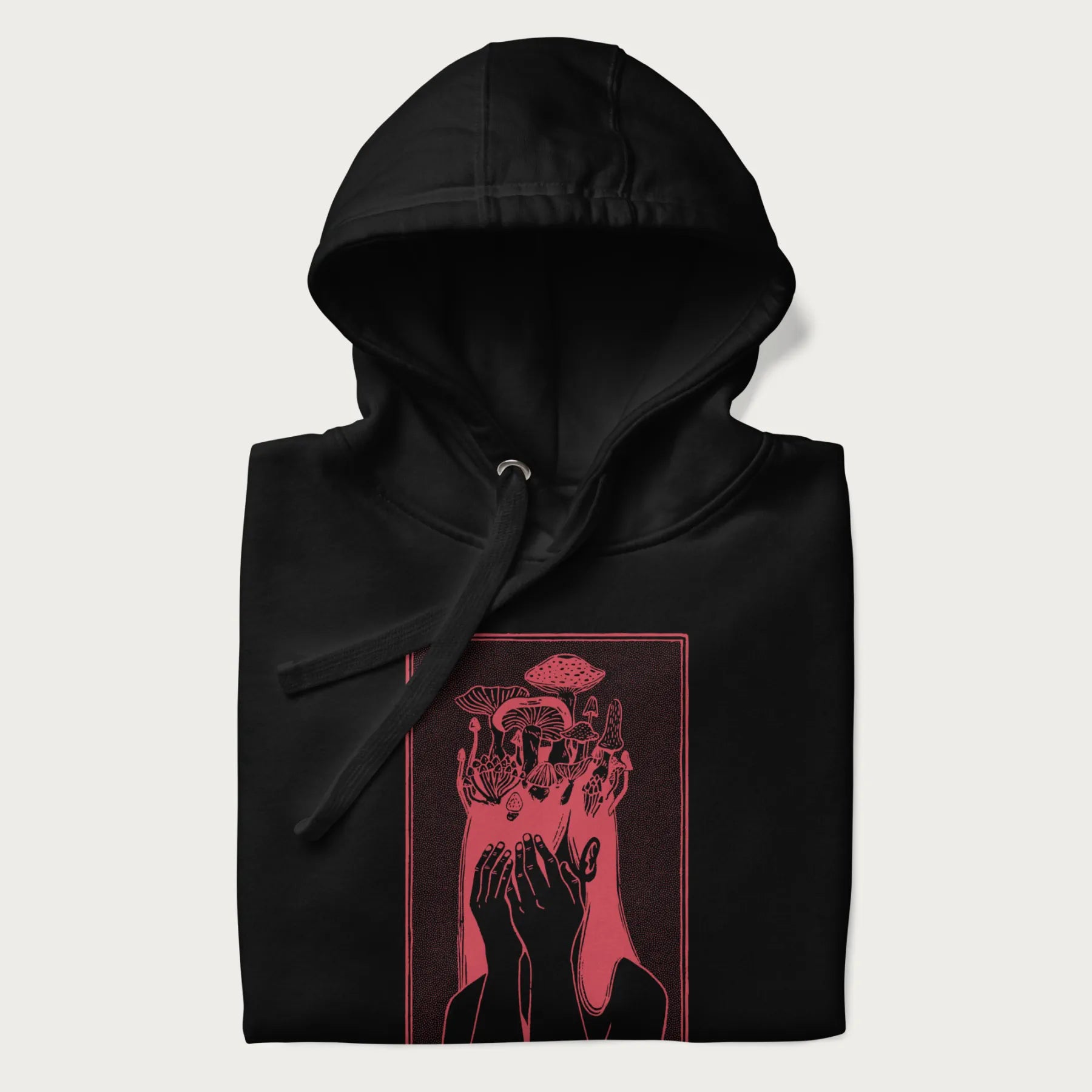 Folded black hoodie with a surreal red graphic of a girl with mushrooms growing from her head.