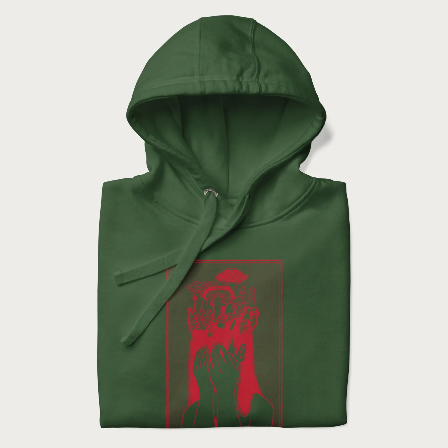 Folded forest green hoodie with a surreal red graphic of a girl with mushrooms growing from her head.