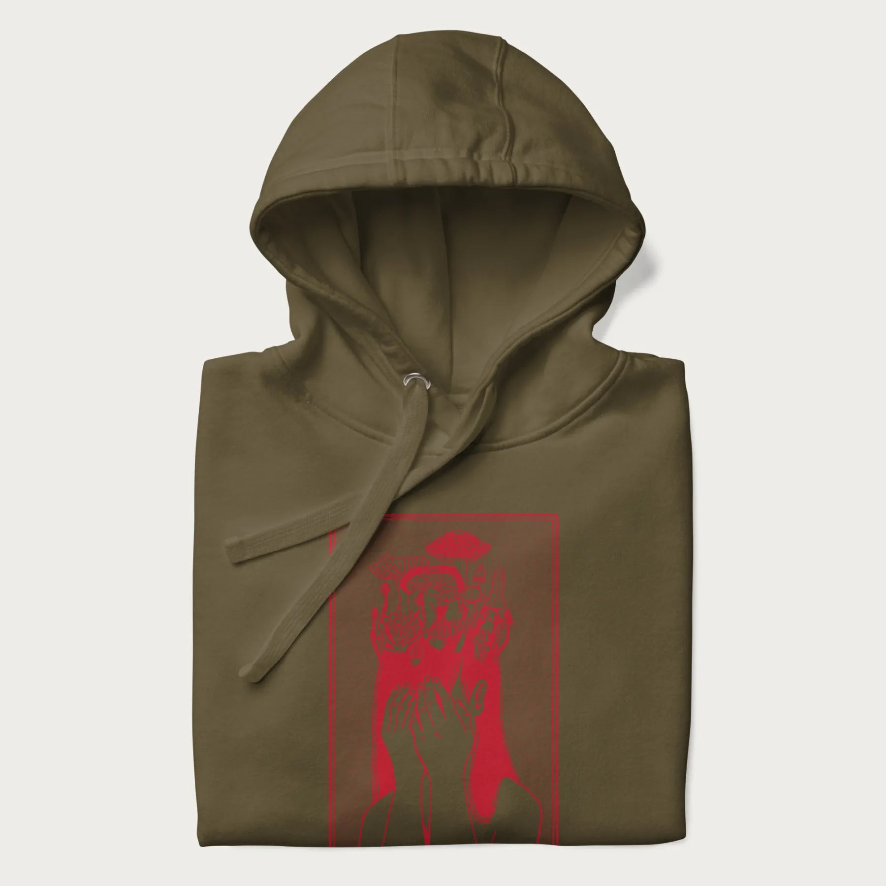 Folded military green hoodie with a surreal red graphic of a girl with mushrooms growing from her head.