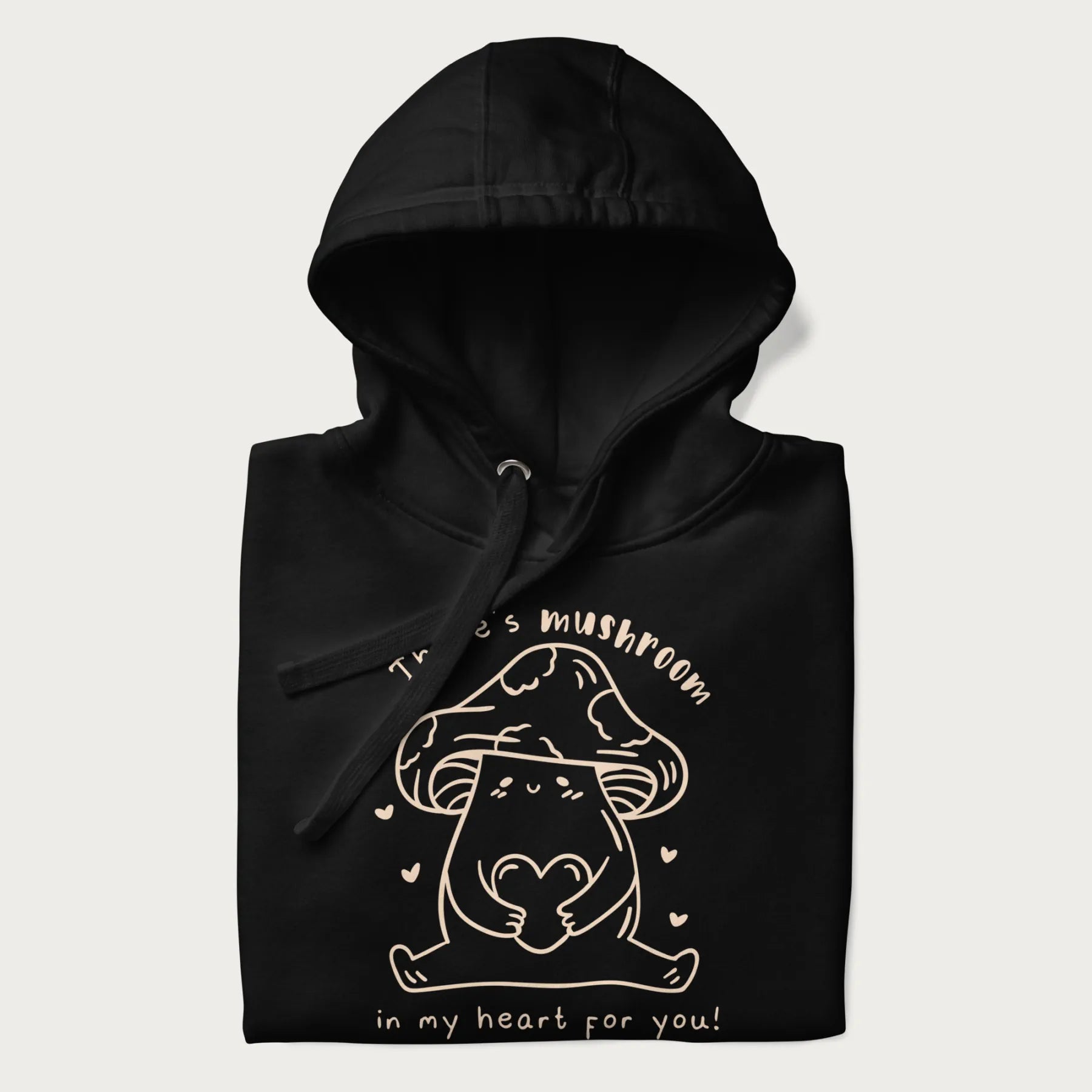 Folded black hoodie with graphic of a cute mushroom holding a heart with the text "There's Mushroom in My Heart for You!"