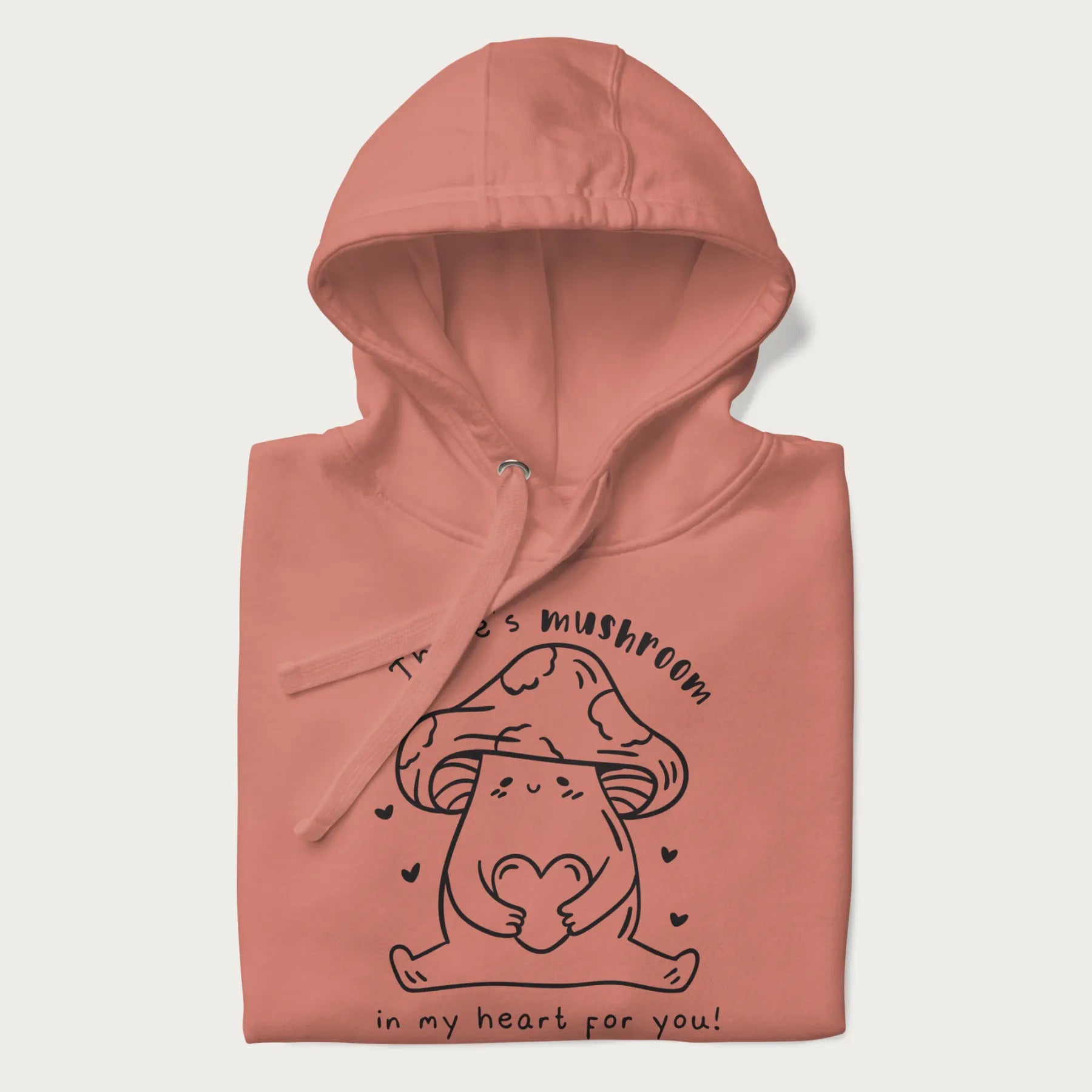Folded light pink hoodie with graphic of a cute mushroom holding a heart with the text "There's Mushroom in My Heart for You!"