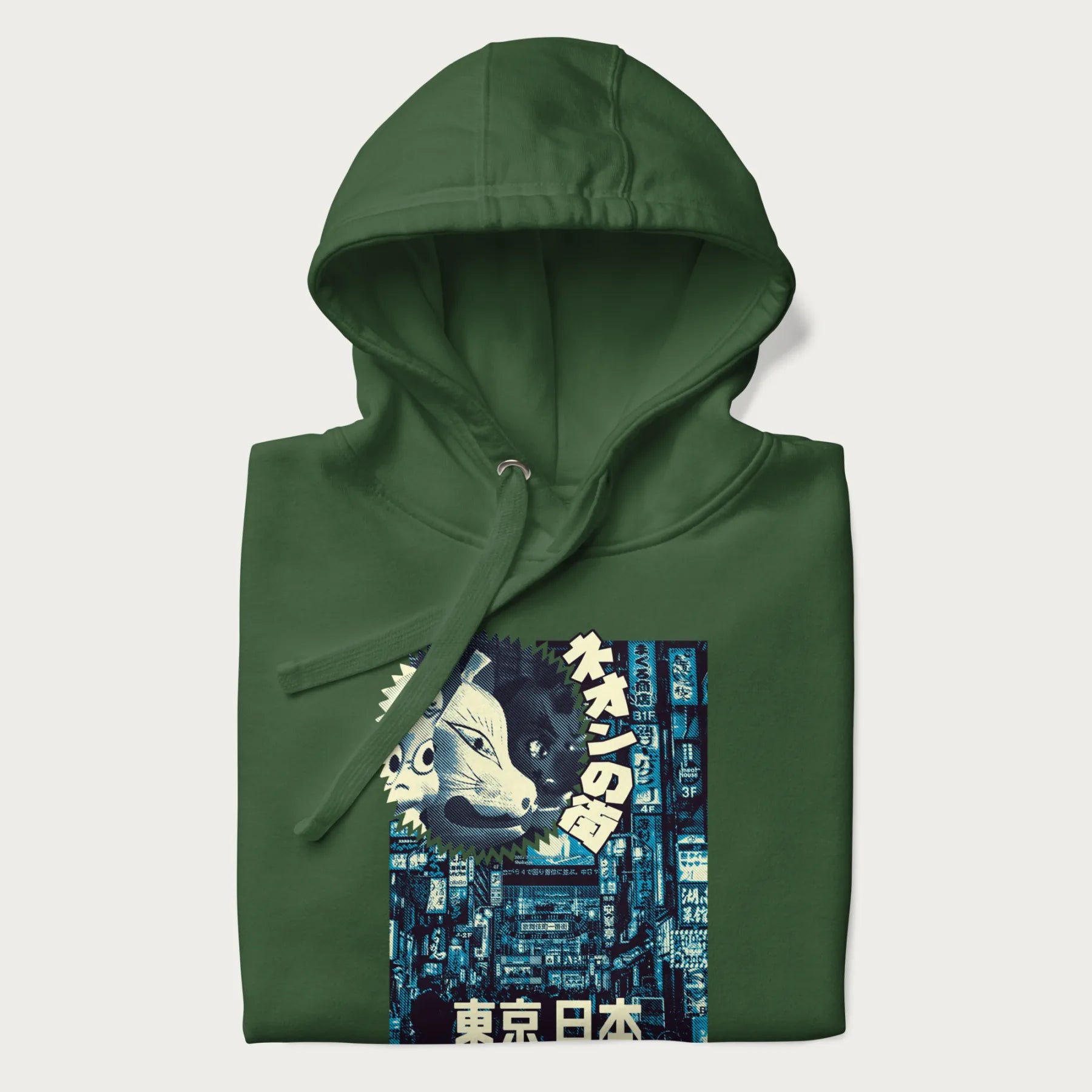 Folded forest green hoodie with Japanese text '東京日本' translating to 'Tokyo, Japan', with three traditional Japanese masks over a neon-lit Tokyo background.