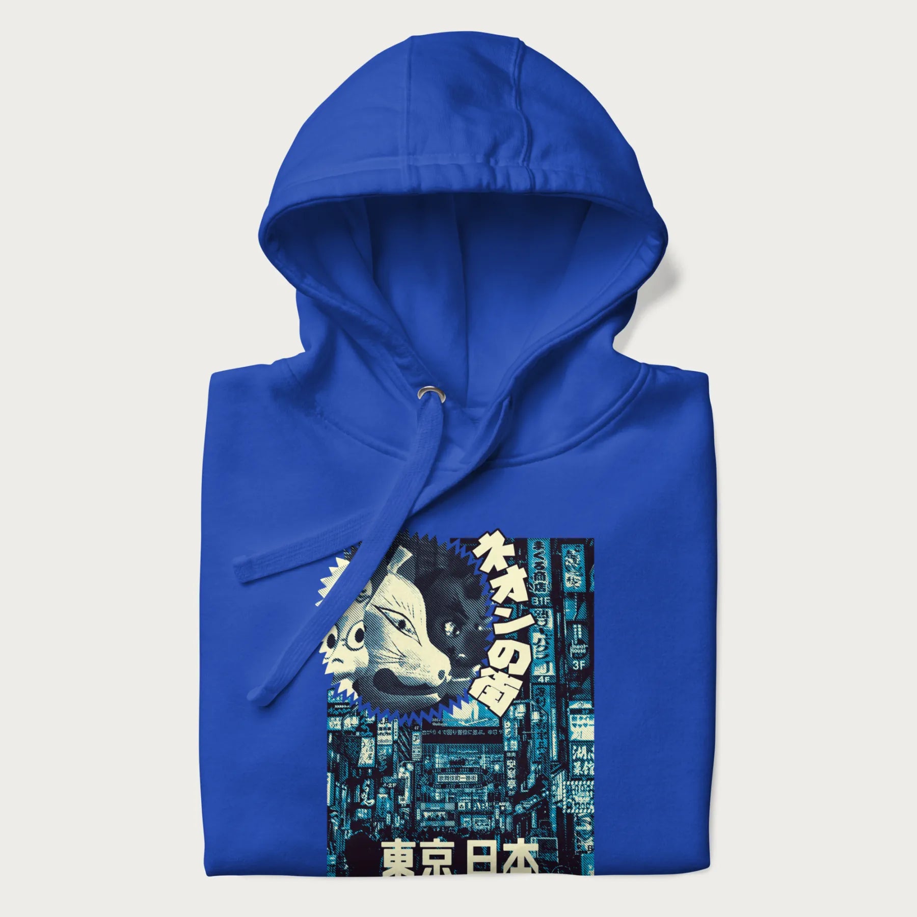 Folded royal blue hoodie with Japanese text '東京日本' translating to 'Tokyo, Japan', with three traditional Japanese masks over a neon-lit Tokyo background.