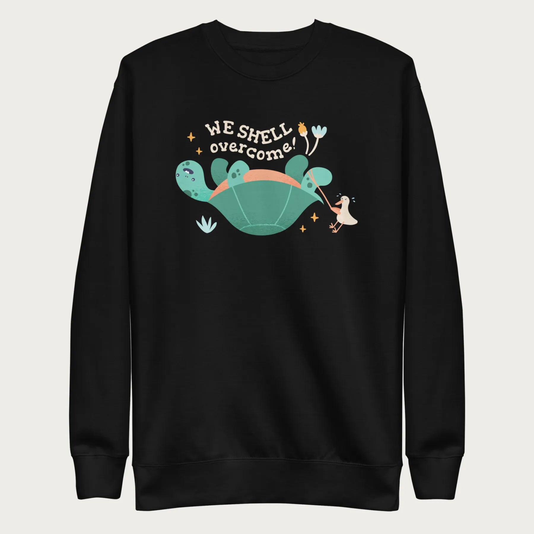 Black sweatshirt with a graphic of a turtle flipped on it's shell with the phrase 'We Shell Overcome.'