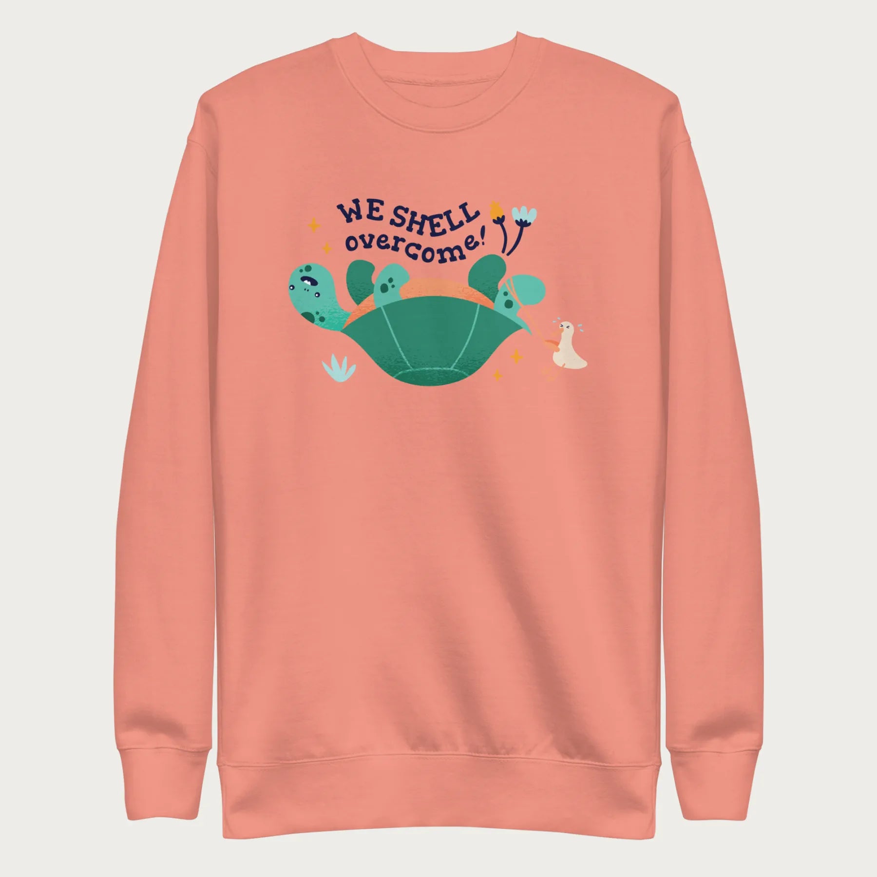 Light pink sweatshirt with a graphic of a turtle flipped on it's shell with the phrase 'We Shell Overcome.'