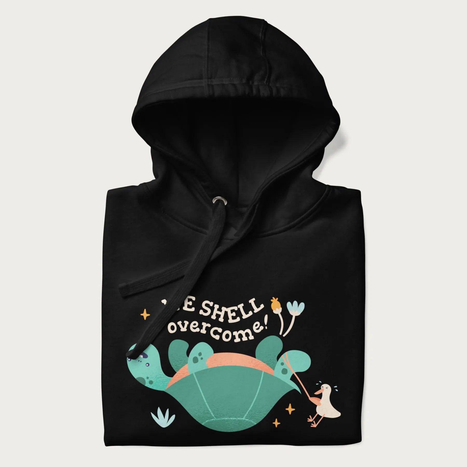 Folded black hoodie with graphic of a turtle and a duck with the text 'We Shell Overcome'.