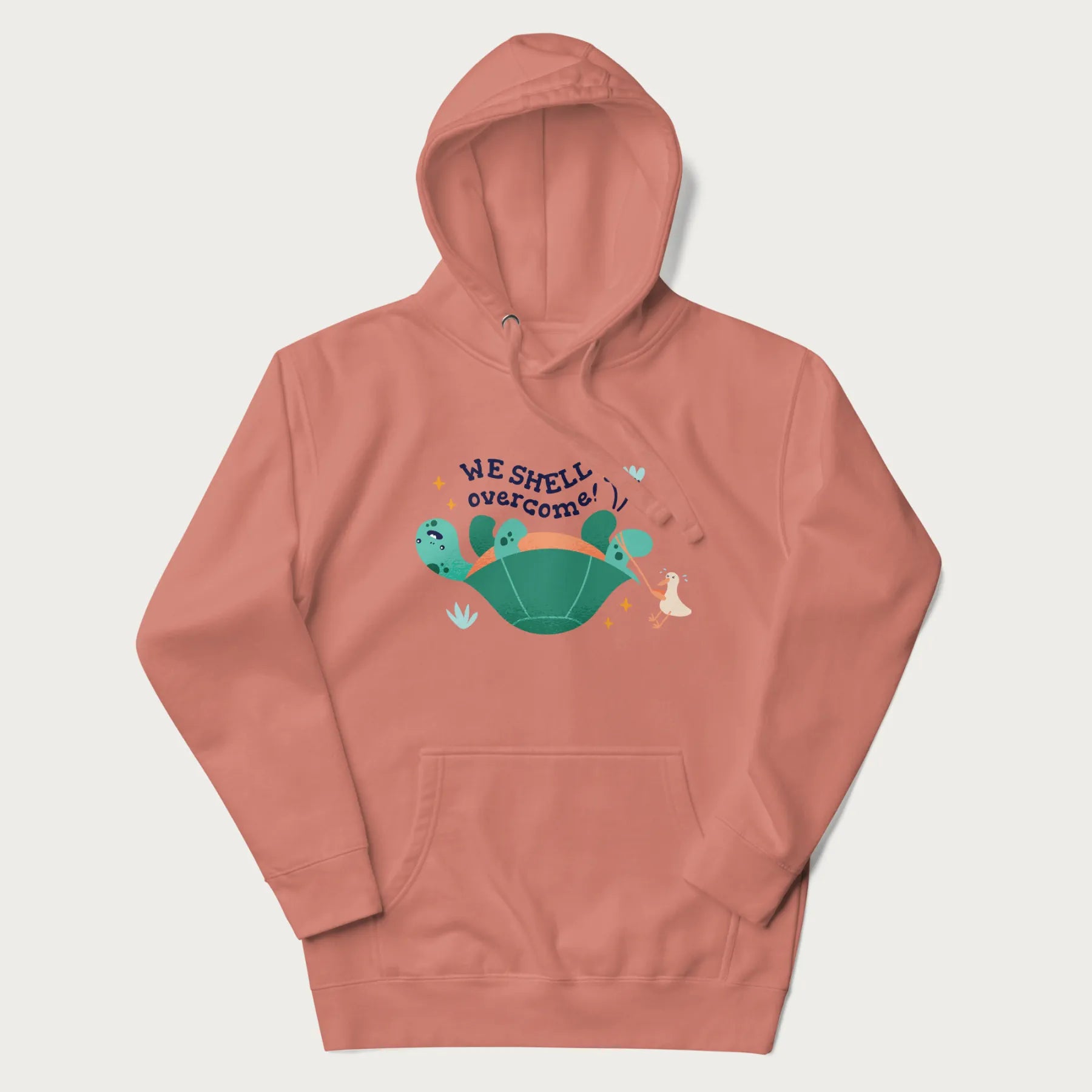 Light pink hoodie with graphic of a turtle and a duck with the text 'We Shell Overcome'.