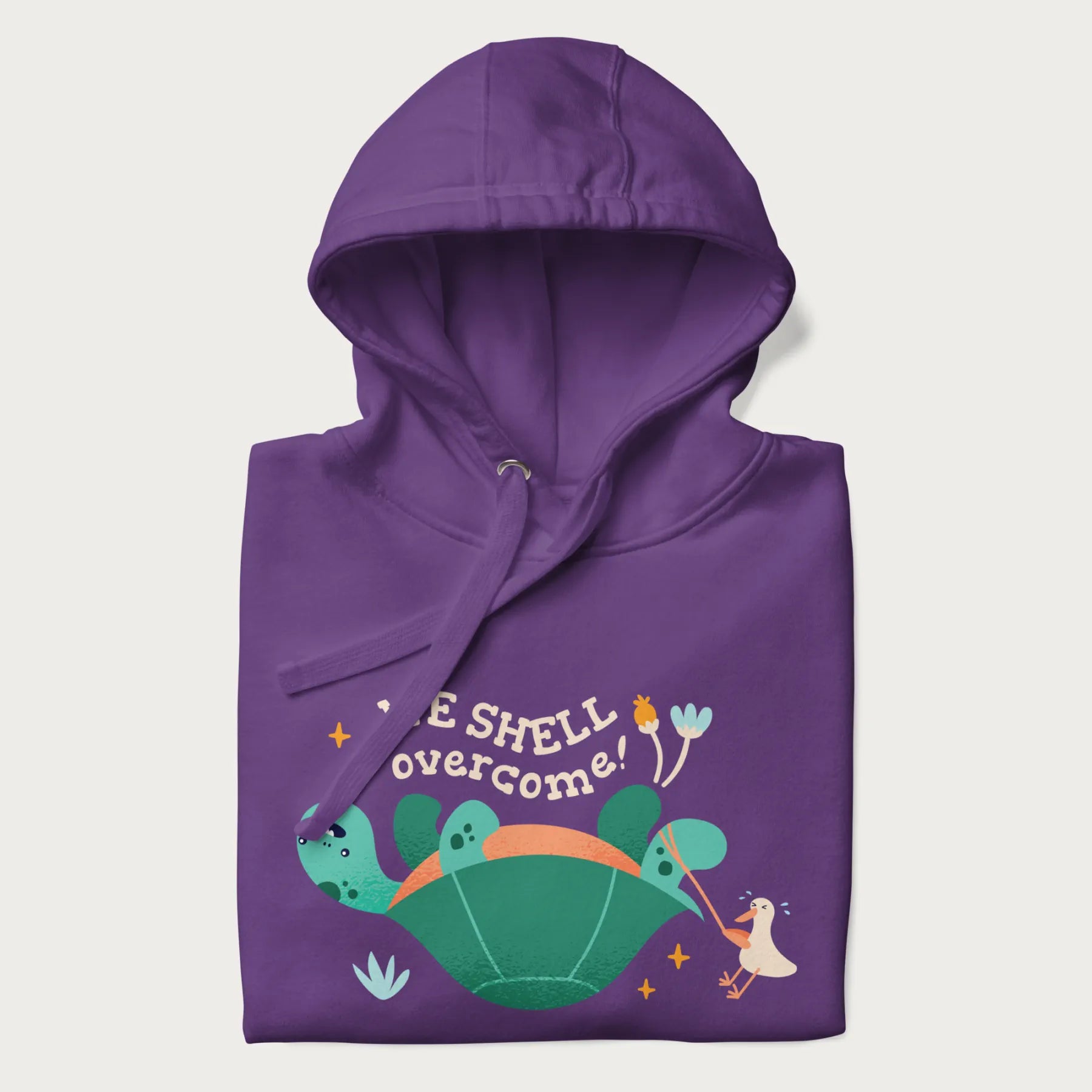 Folded purple hoodie with graphic of a turtle and a duck with the text 'We Shell Overcome'.