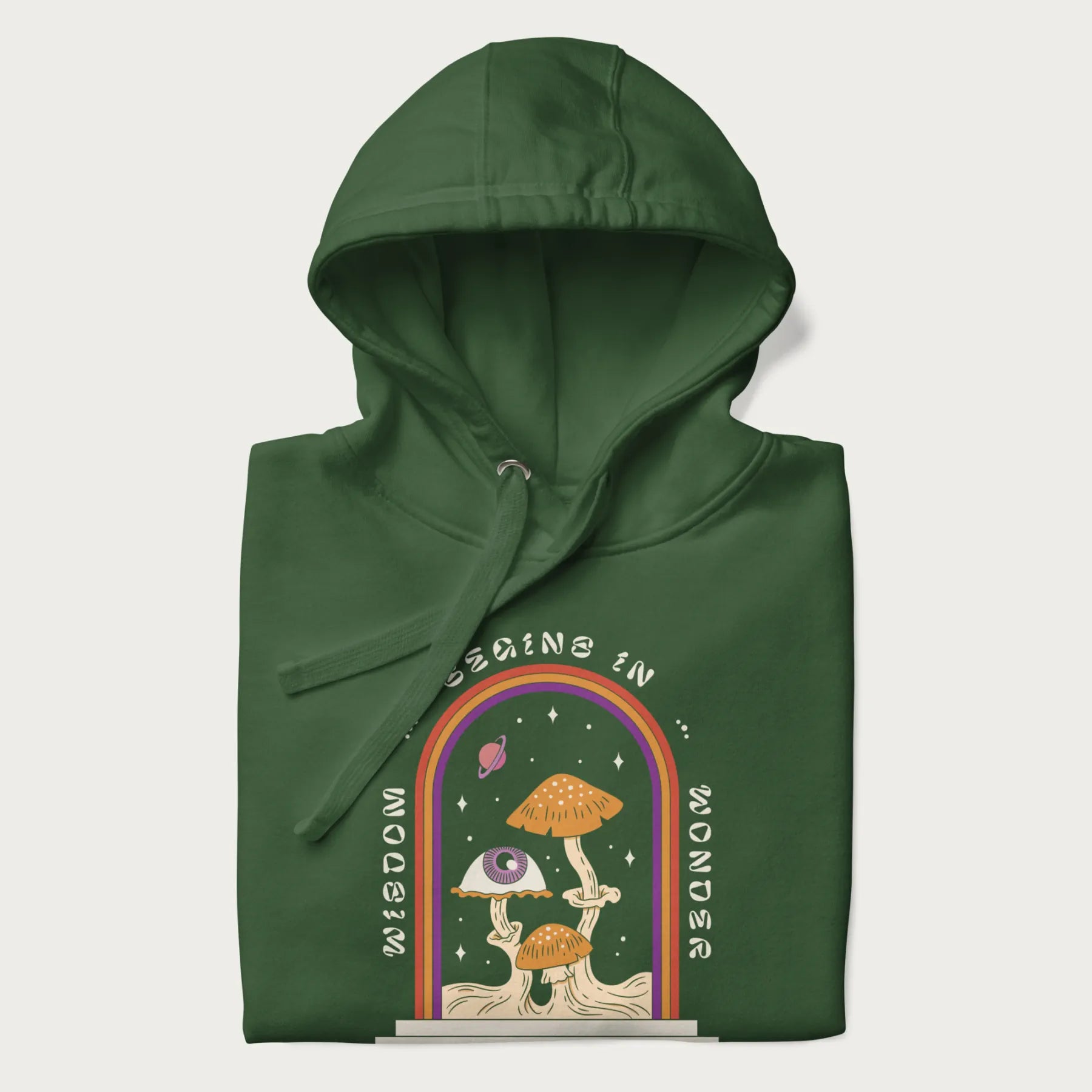 Folded forest green hoodie with graphic of mystical mushrooms with an all-seeing eye and the text 'Wisdom Begins in Wonder' framed by a rainbow arch.