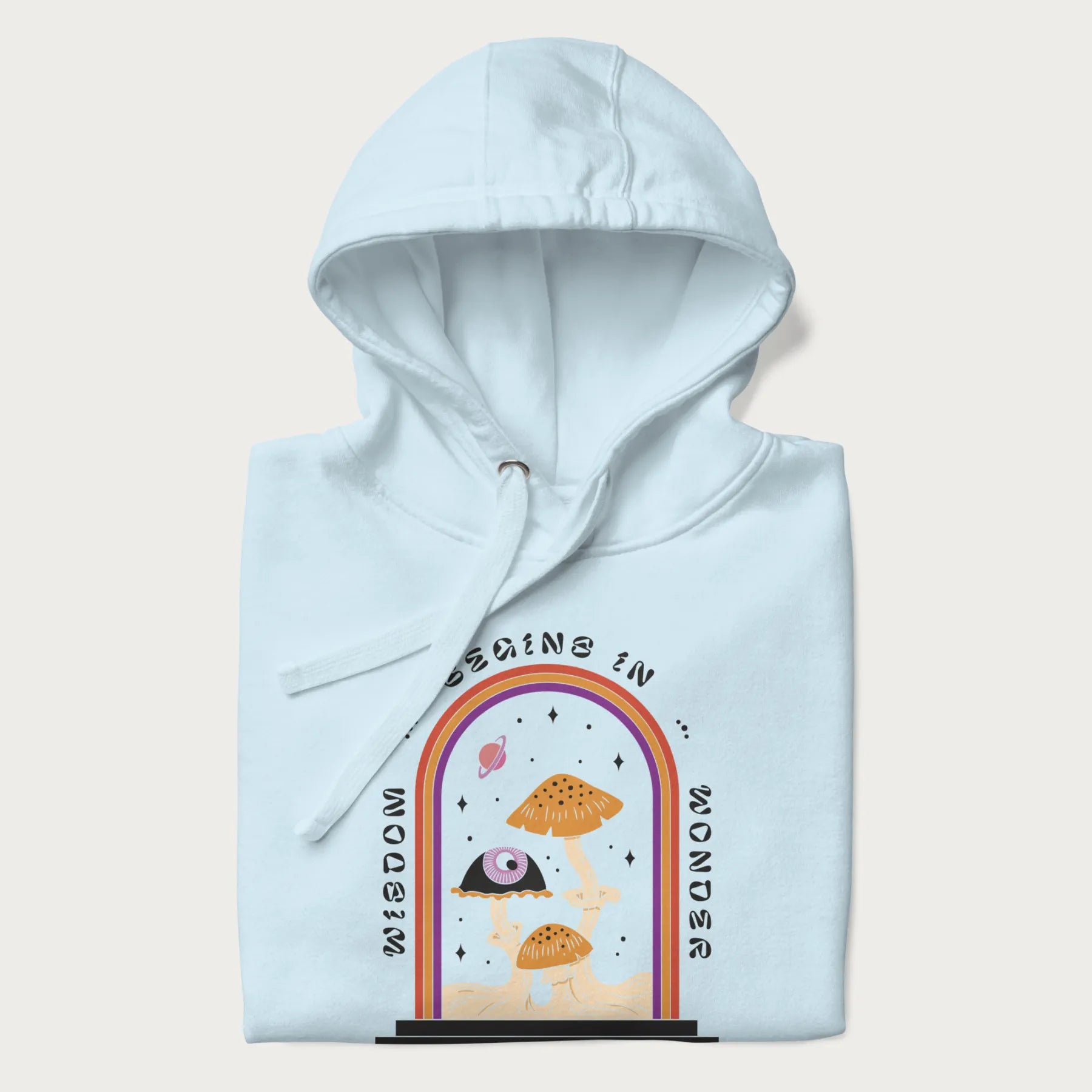Folded light blue hoodie with graphic of mystical mushrooms with an all-seeing eye and the text 'Wisdom Begins in Wonder' framed by a rainbow arch.