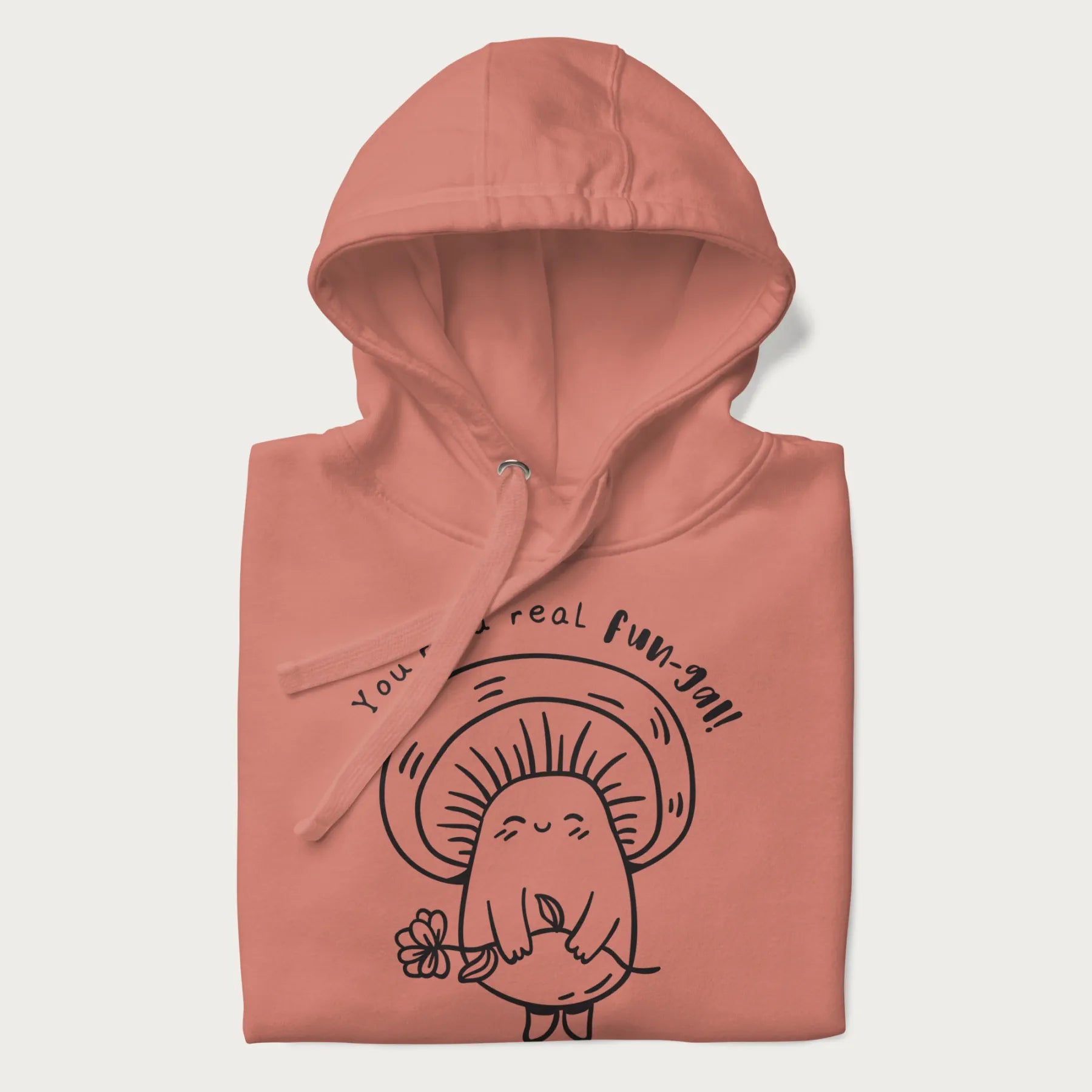 Folded light pink hoodie with graphic of a cute mushroom holding a flower and the text "You're a Real Fun-gal!"