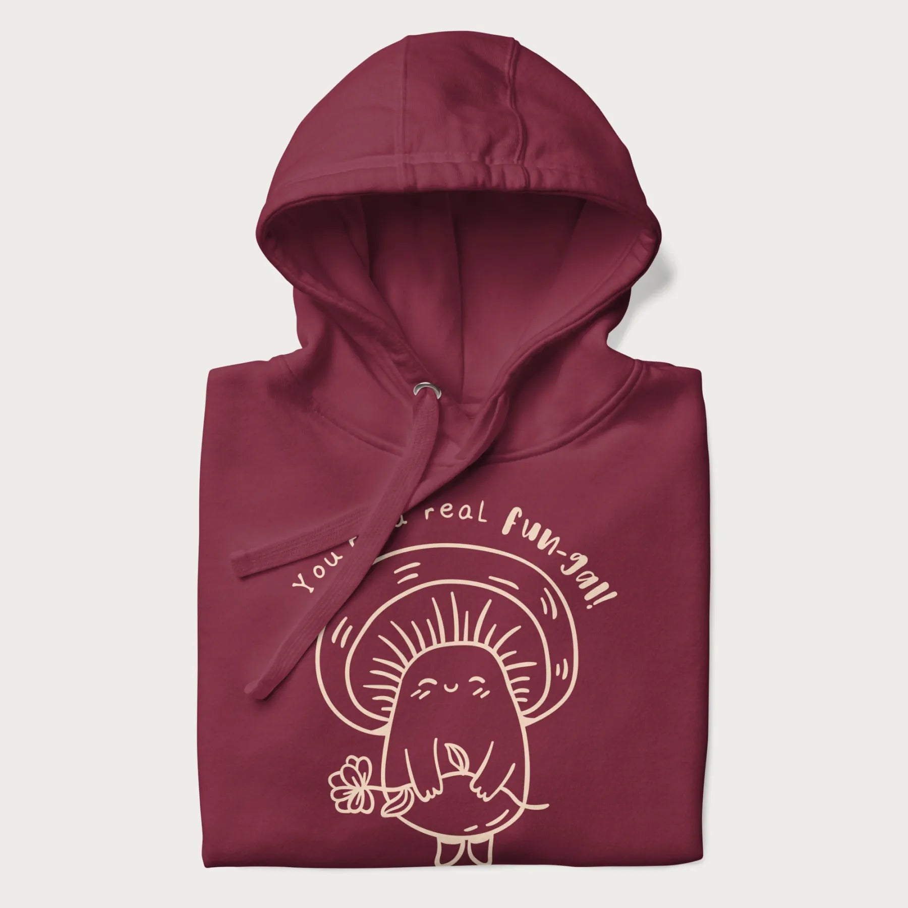 Folded maroon hoodie with graphic of a cute mushroom holding a flower and the text "You're a Real Fun-gal!"