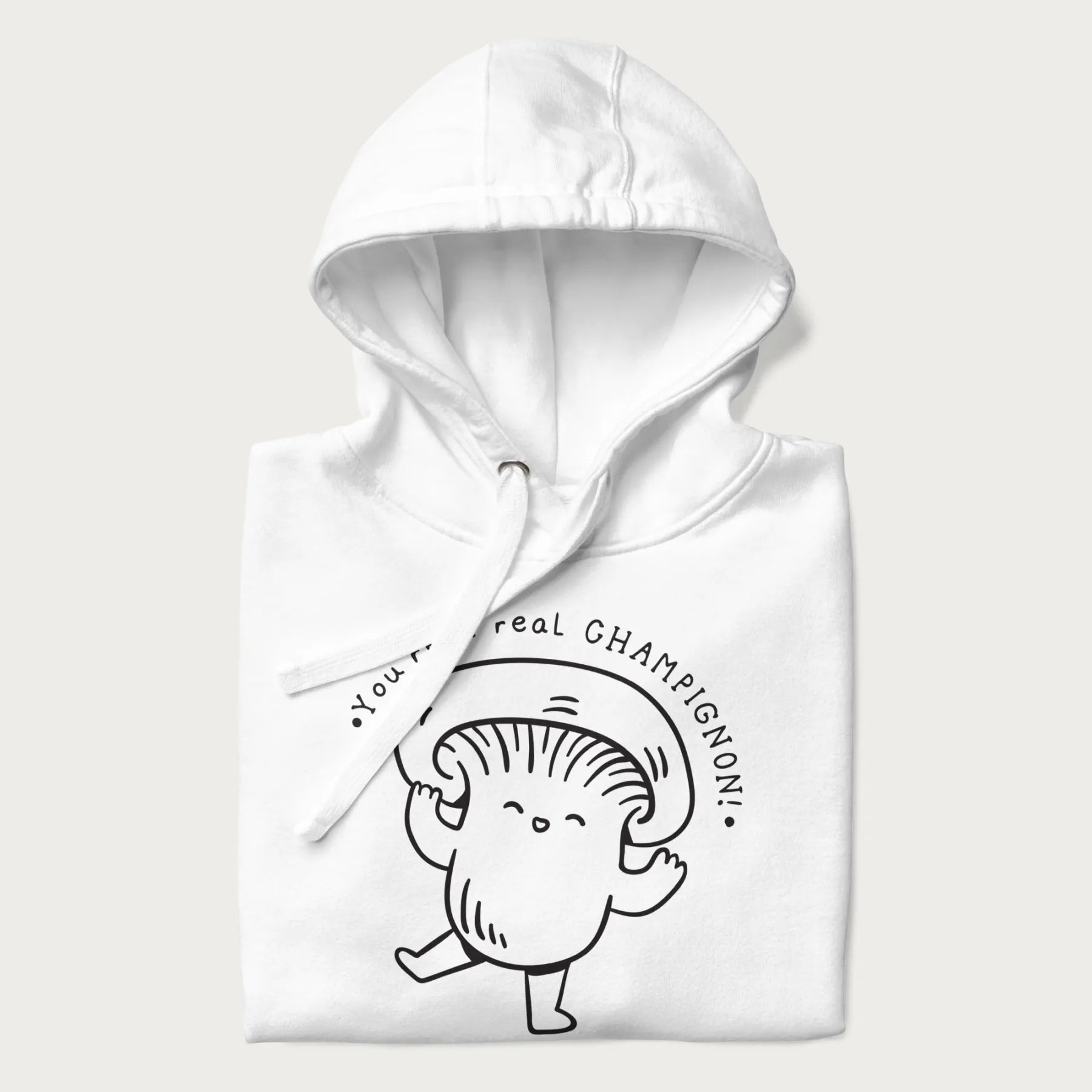 Folded white hoodie with a cute champignon mushroom graphic and the text "You're a Real Champignon!"