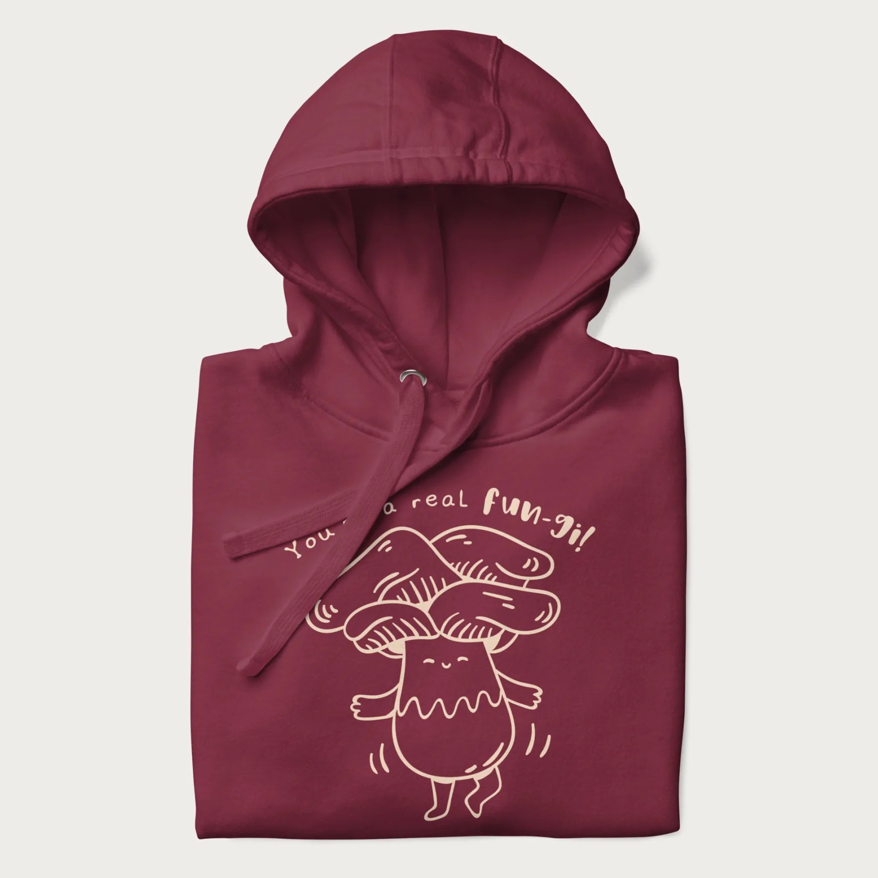 Folded maroon hoodie with graphic of a cute mushroom joyfully dancing with the text "You're a Real Fun-gi!"