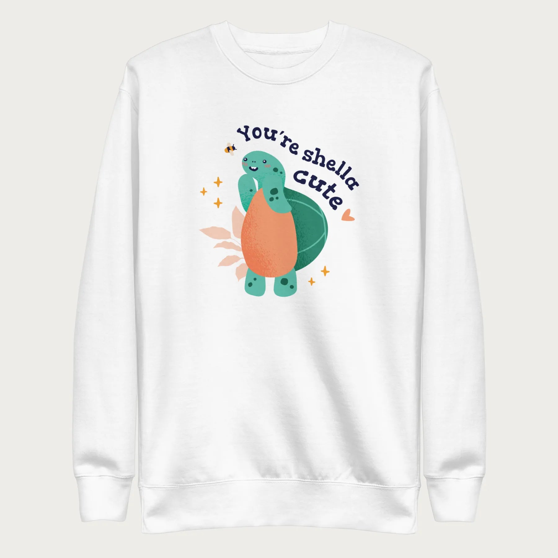 White sweatshirt with a cute graphic of a smiling turtle and bee with the phrase 'You're Shella Cute.'