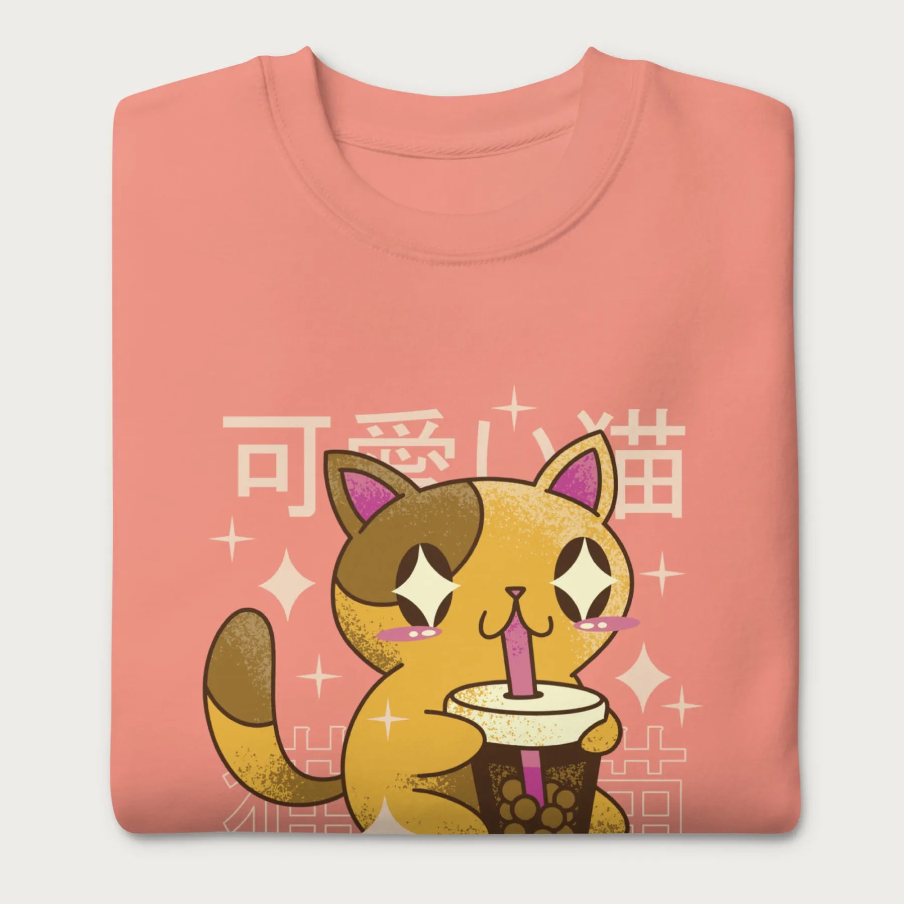 Folded light pink sweatshirt with Japanese text and a kawaii graphic of a cat drinking bubble tea.