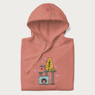 Folded light pink hoodie with graphic of a tabby cat on a scratching post, raising its middle finger.