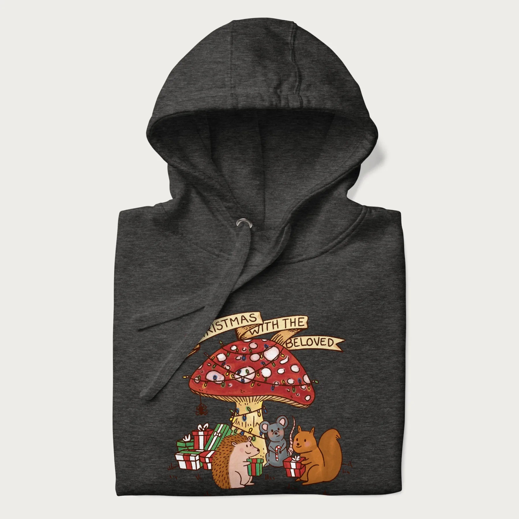 Folded dark grey hoodie with animal around a festively decorated mushroom and the text 'Christmas with the Beloved' above.