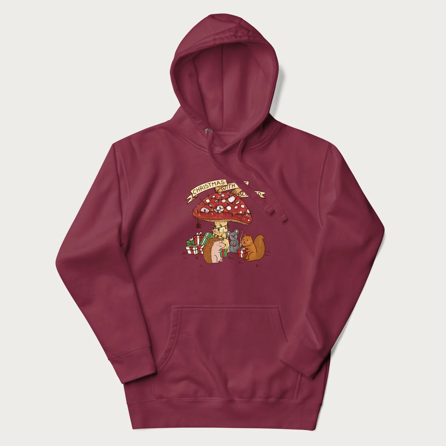 Maroon hoodie with animal around a festively decorated mushroom and the text 'Christmas with the Beloved' above.