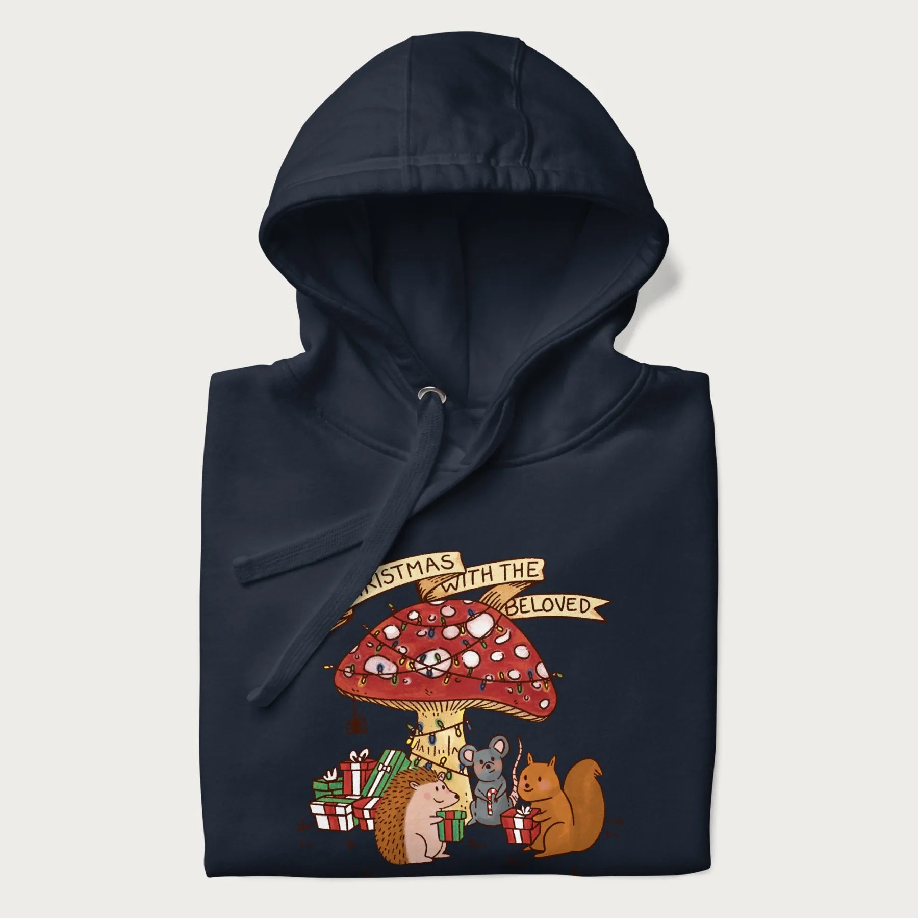 Folded navy blue hoodie with animal around a festively decorated mushroom and the text 'Christmas with the Beloved' above.