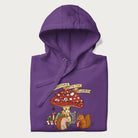 Folded purple hoodie with animal around a festively decorated mushroom and the text 'Christmas with the Beloved' above.