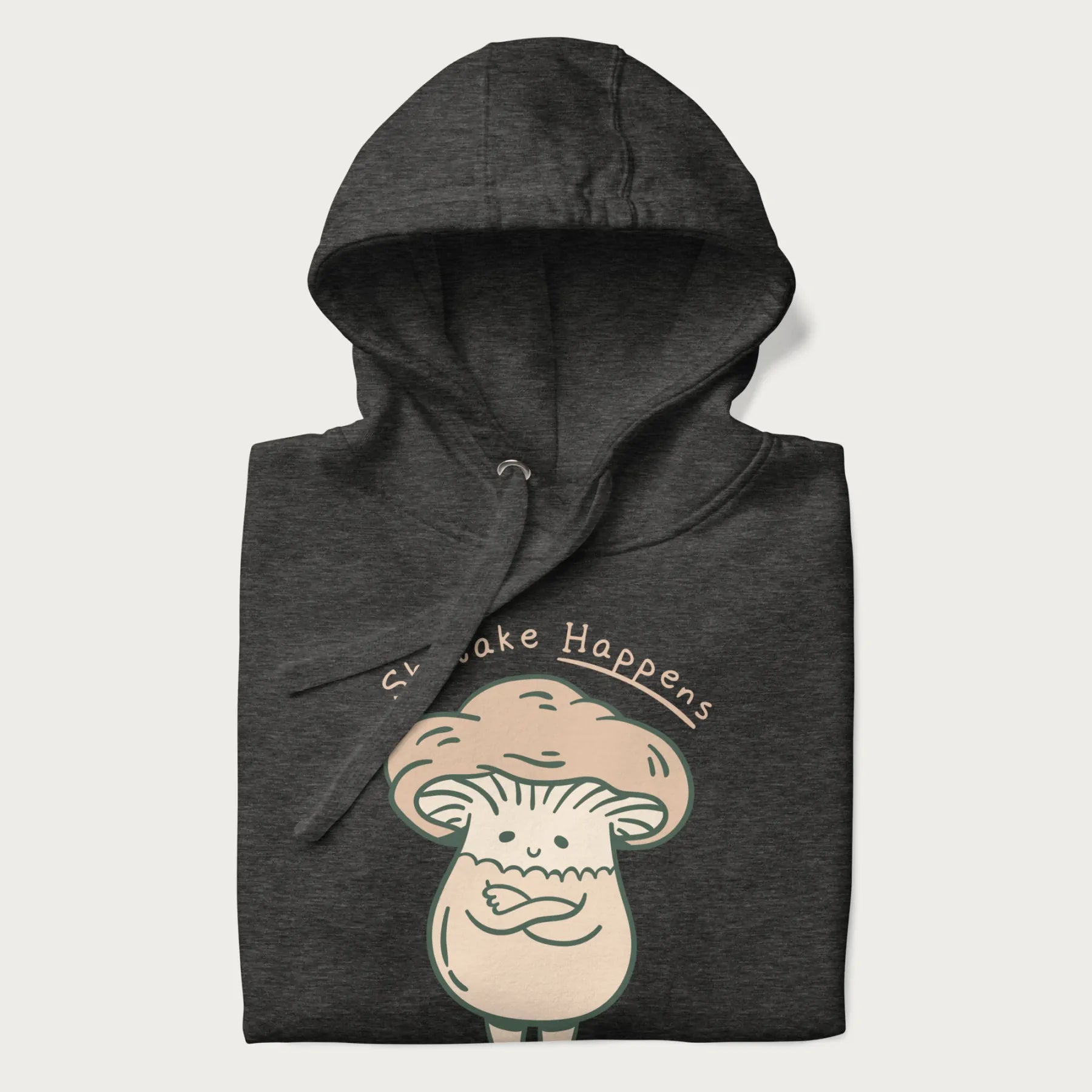 Folded dark grey hoodie with a graphic of an adorable mushroom character and the text 'Shiitake Happens'.
