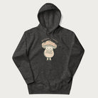 Dark grey hoodie with a graphic of an adorable mushroom character and the text 'Shiitake Happens'.