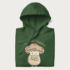 Folded forest green hoodie with a graphic of an adorable mushroom character and the text 'Shiitake Happens'.