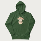 Forest green hoodie with a graphic of an adorable mushroom character and the text 'Shiitake Happens'.