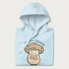 Folded light blue hoodie with a graphic of an adorable mushroom character and the text 'Shiitake Happens'.