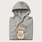 Folded light grey hoodie with a graphic of an adorable mushroom character and the text 'Shiitake Happens'.