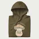 Folded military green hoodie with a graphic of an adorable mushroom character and the text 'Shiitake Happens'.
