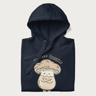 Folded navy blue hoodie with a graphic of an adorable mushroom character and the text 'Shiitake Happens'.