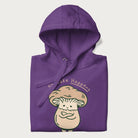Folded purple hoodie with a graphic of an adorable mushroom character and the text 'Shiitake Happens'.