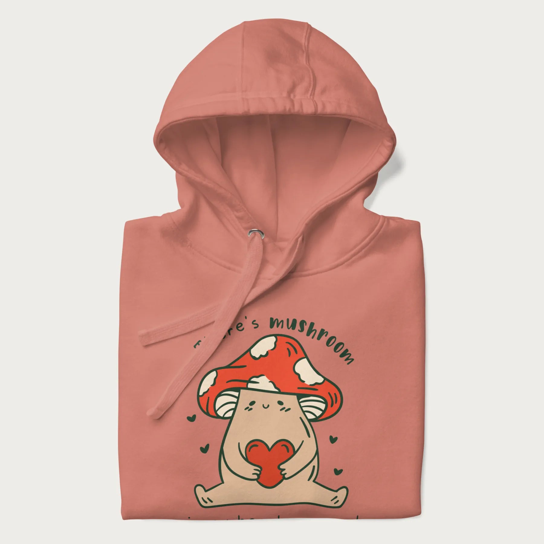 Folded light pink hoodie with a graphic of a mushroom character holding a heart and the text 'There's Mushroom in My Heart for You'.