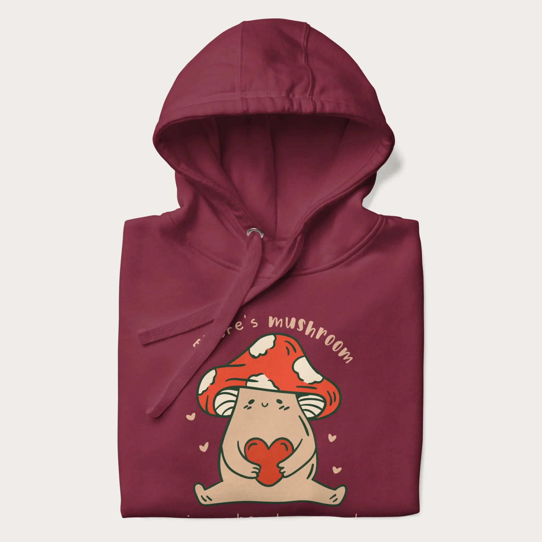 Folded maroon hoodie with a graphic of a mushroom character holding a heart and the text 'There's Mushroom in My Heart for You'.