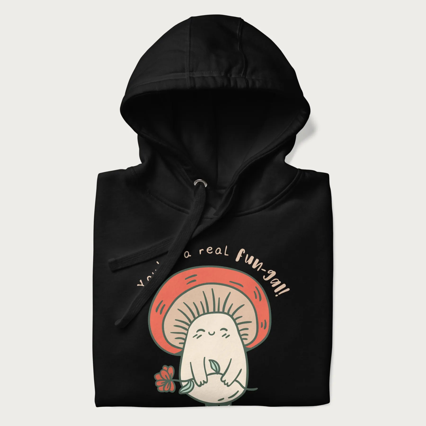 Folded black hoodie with a graphic of a cute mushroom character holding a flower and the text 'You're a real fun-gal!'.