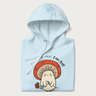 Folded light blue hoodie with a graphic of a cute mushroom character holding a flower and the text 'You're a real fun-gal!'.