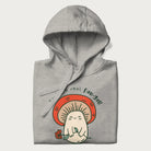 Folded light grey hoodie with a graphic of a cute mushroom character holding a flower and the text 'You're a real fun-gal!'.