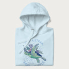 Folded light blue hoodie with a graphic of a sea turtle with coral on it's shell and the text 'Skip a Straw, Save a Turtle'.