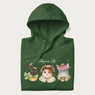 Folded forest green hoodie with a graphic of three cats in vintage-inspired attire and the text 'Cottagecore Cats'.