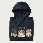 Folded navy blue hoodie with a graphic of three cats in vintage-inspired attire and the text 'Cottagecore Cats'.