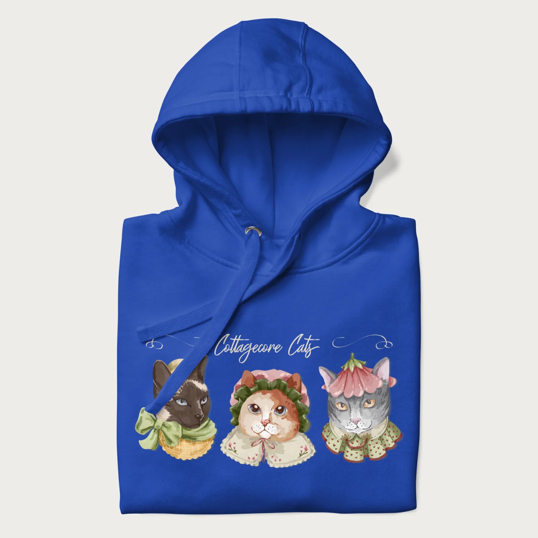 Folded royal blue hoodie with a graphic of three cats in vintage-inspired attire and the text 'Cottagecore Cats'.