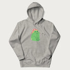 Light grey hoodie with a graphic of a green frog wearing a mushroom cap surrounded by stars.