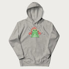 Light grey hoodie will illustration of a cute green frog with red and white mushrooms.