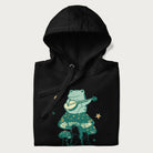 Folded black hoodie with graphic of a frog playing a banjo on a mushroom with stars and a crescent moon.