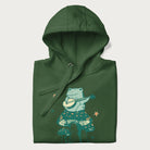 Folded forest green hoodie with graphic of a frog playing a banjo on a mushroom with stars and a crescent moon.